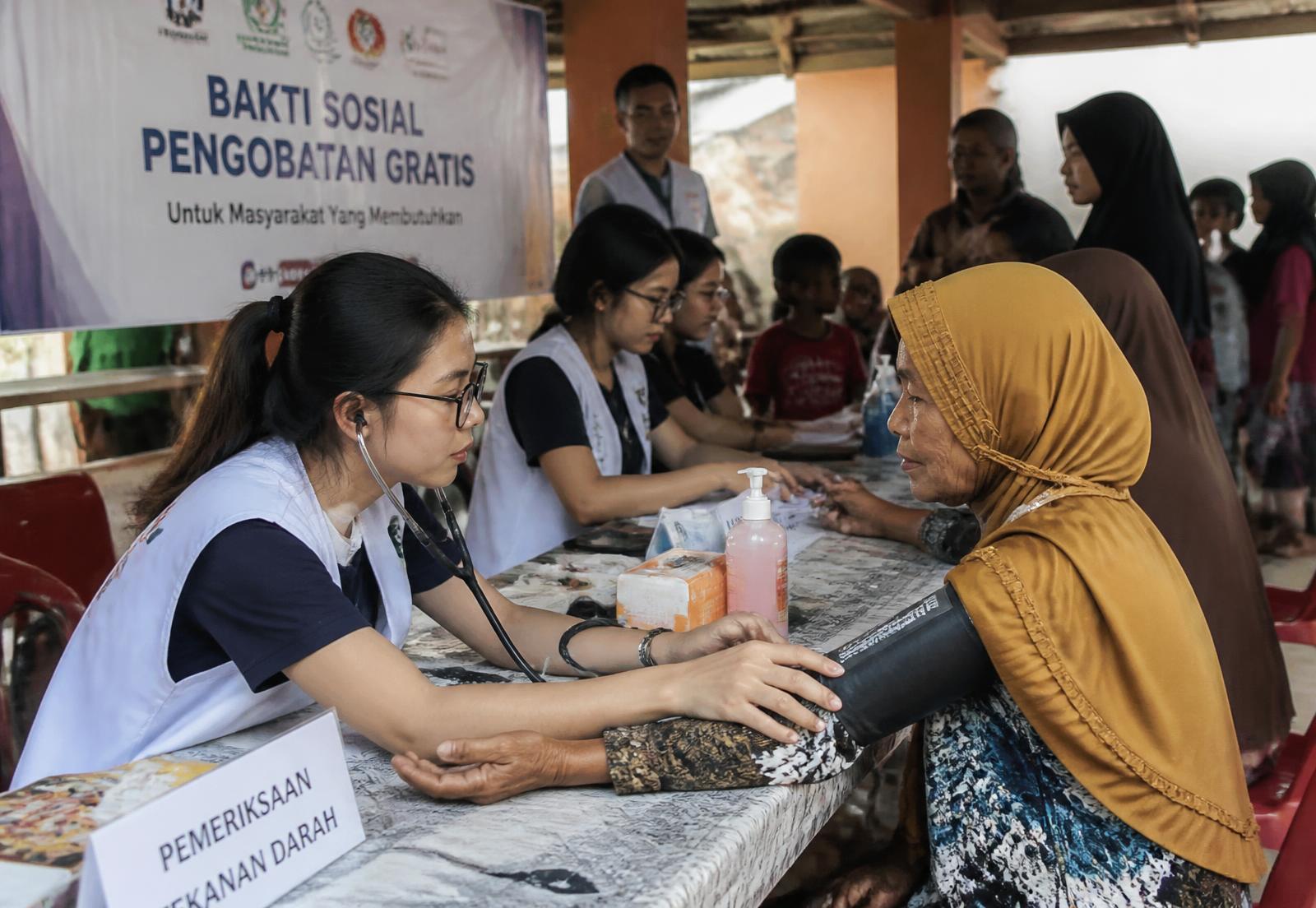 Relawan medis memeriksa tekanan darah seorang lansia pada bakti sosial pengobatan gratis
