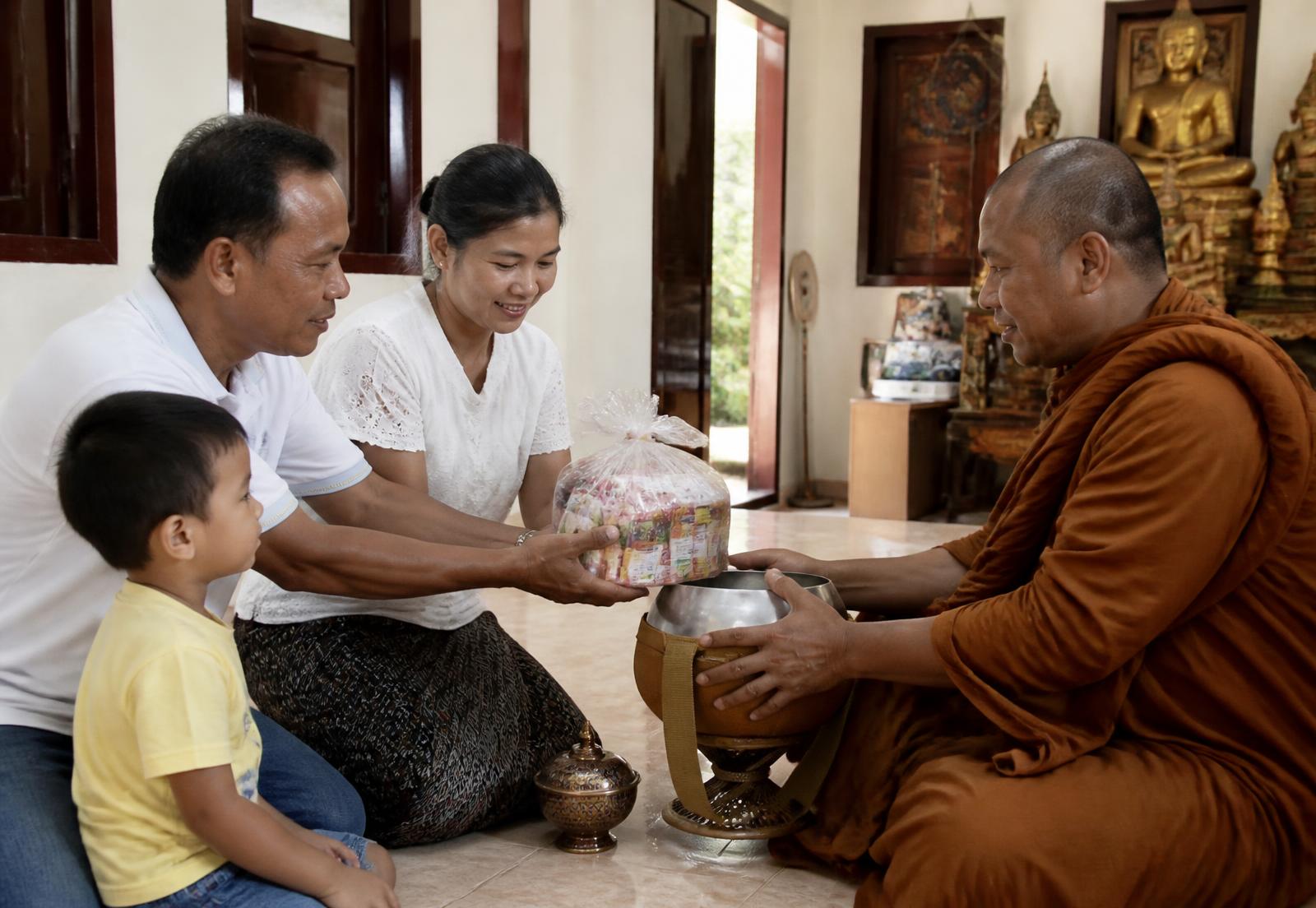 Keluarga umat mempersembahkan dana kepada seorang bhikkhu di vihara