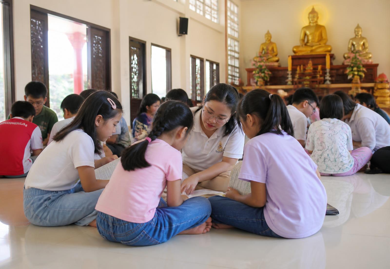 Anak-anak Sekolah Minggu Buddha belajar Dhamma bersama guru relawan di ruang vihara